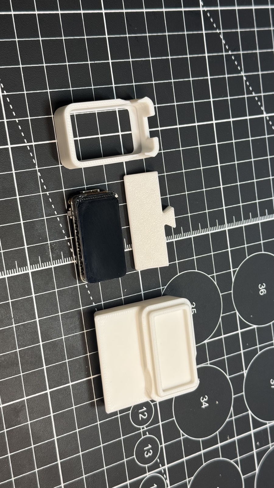 Three white printed parts (frame, foot and stand) and the bare ESP32-C6 board on a cutting mat