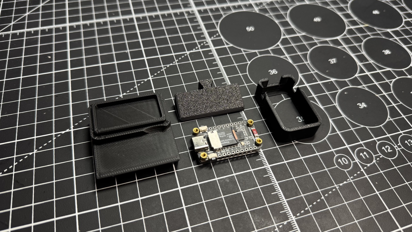 The three printed stand parts and the ESP32-C6 board laid out on a cutting mat